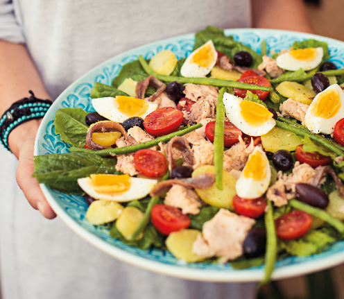 Image of a salad with egg, tomatoes, cucumber, tuna, green beans and lettuce.